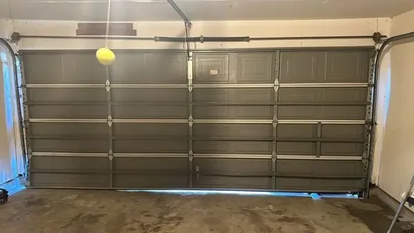 Completed garage door track and panel realignment inside a Dallas-area garage, photographed on-site after the repair